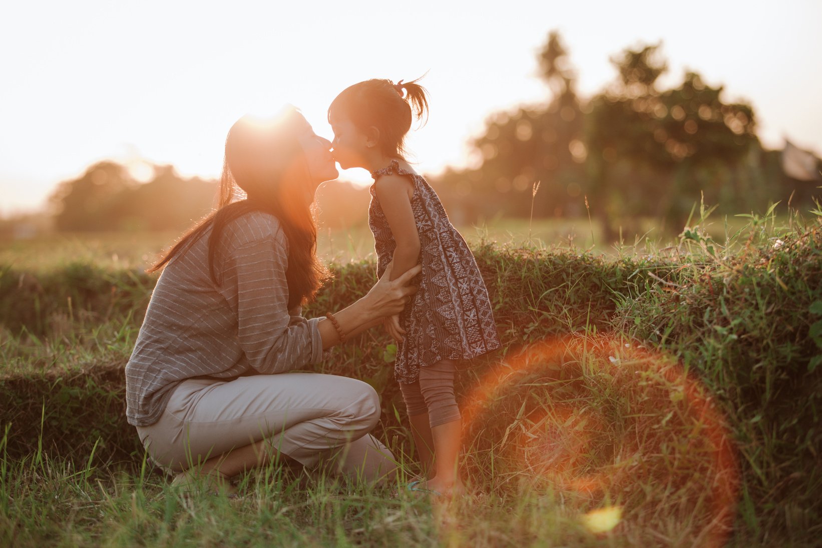 Mom and Kid Kissing under the Sunset Sky